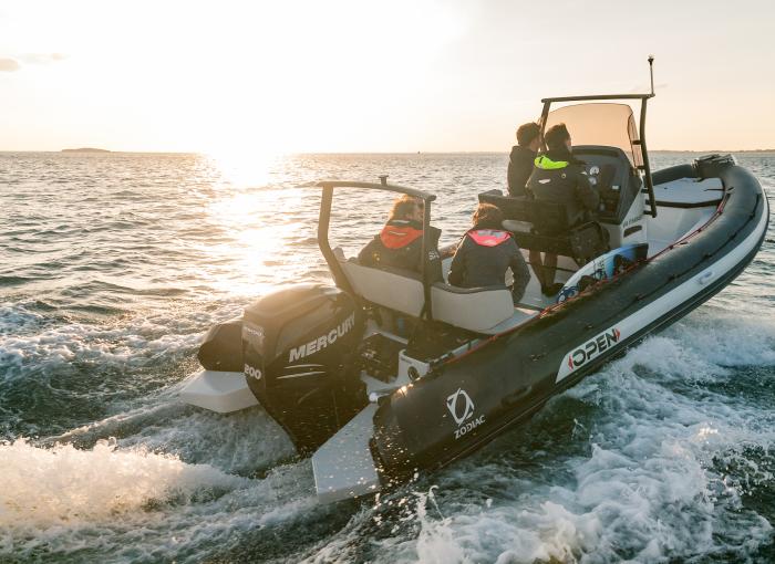 4 people cruising open water in a Zodiac Boat